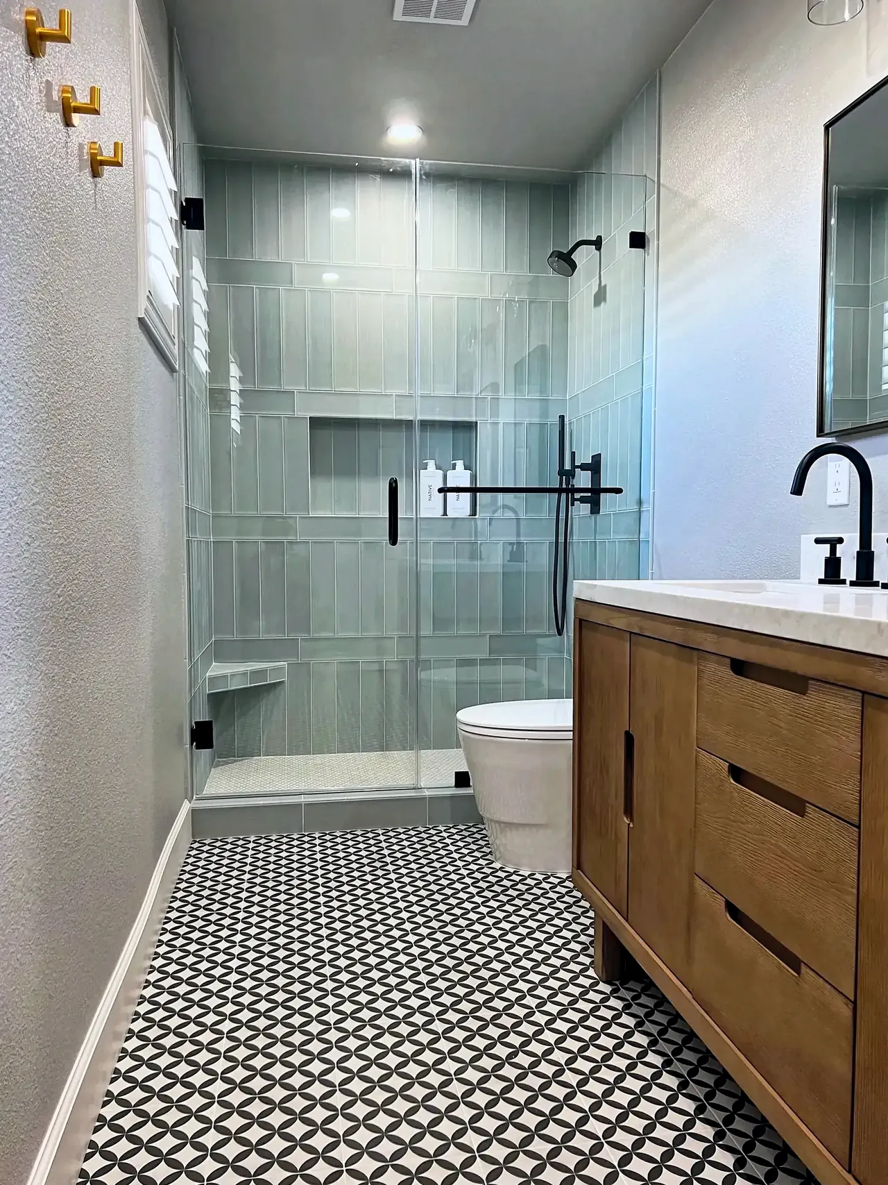 Guest bathroom with a frameless glass walk-in shower in sage vertical tile, a niche and a corner bench