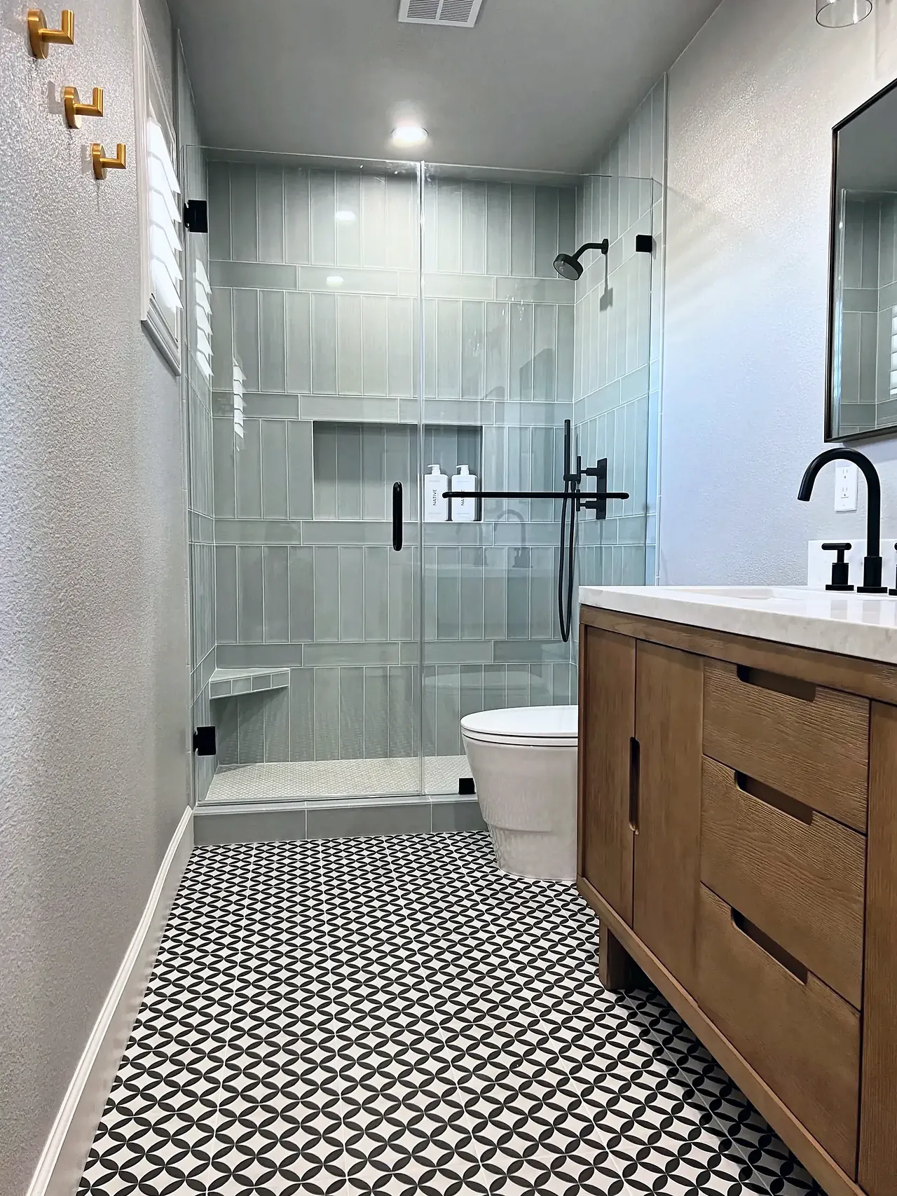 Guest bathroom with a frameless glass walk-in shower in sage vertical tile, a niche and a corner bench