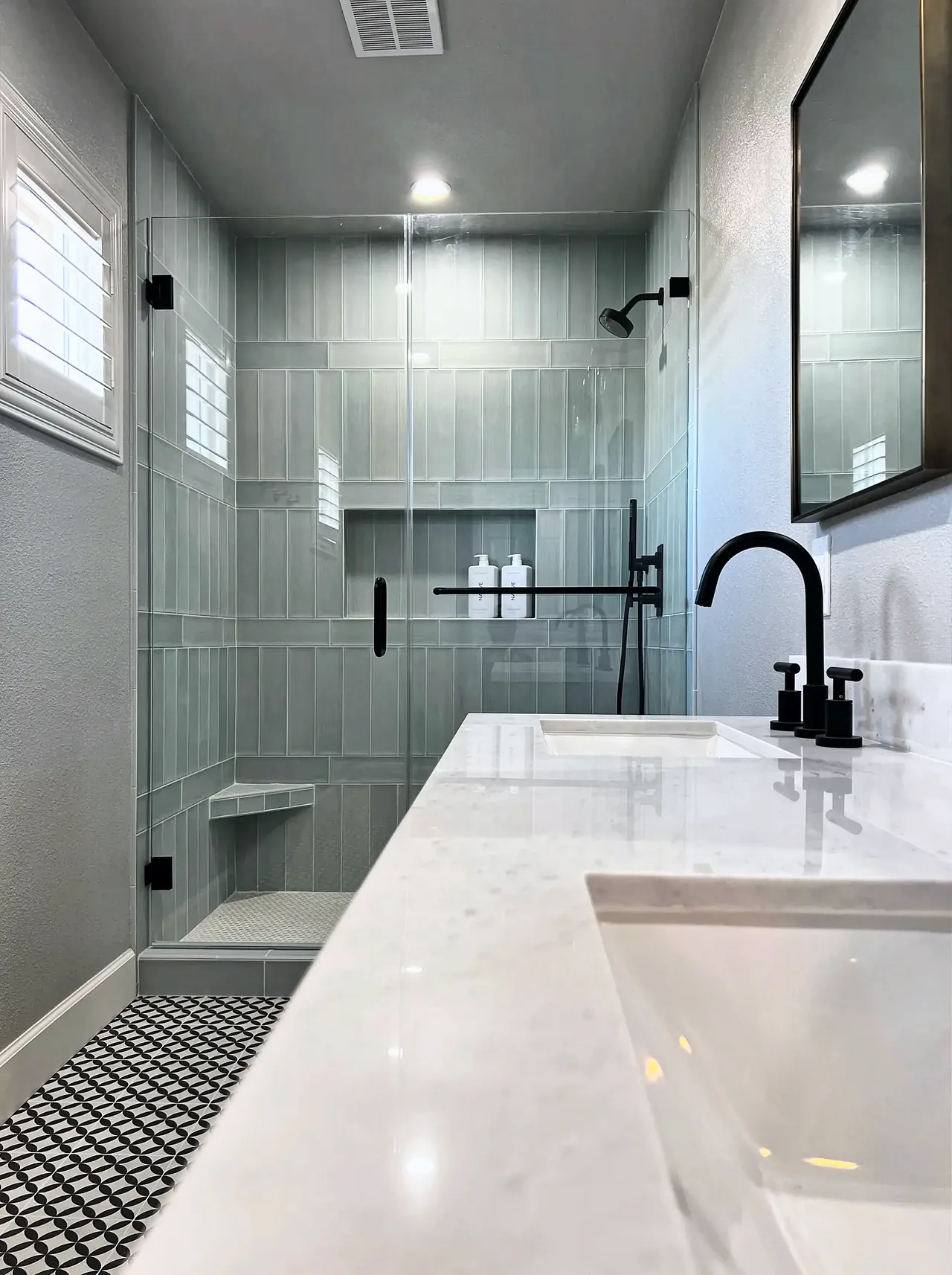 White marble-look vanity looking toward the glass shower