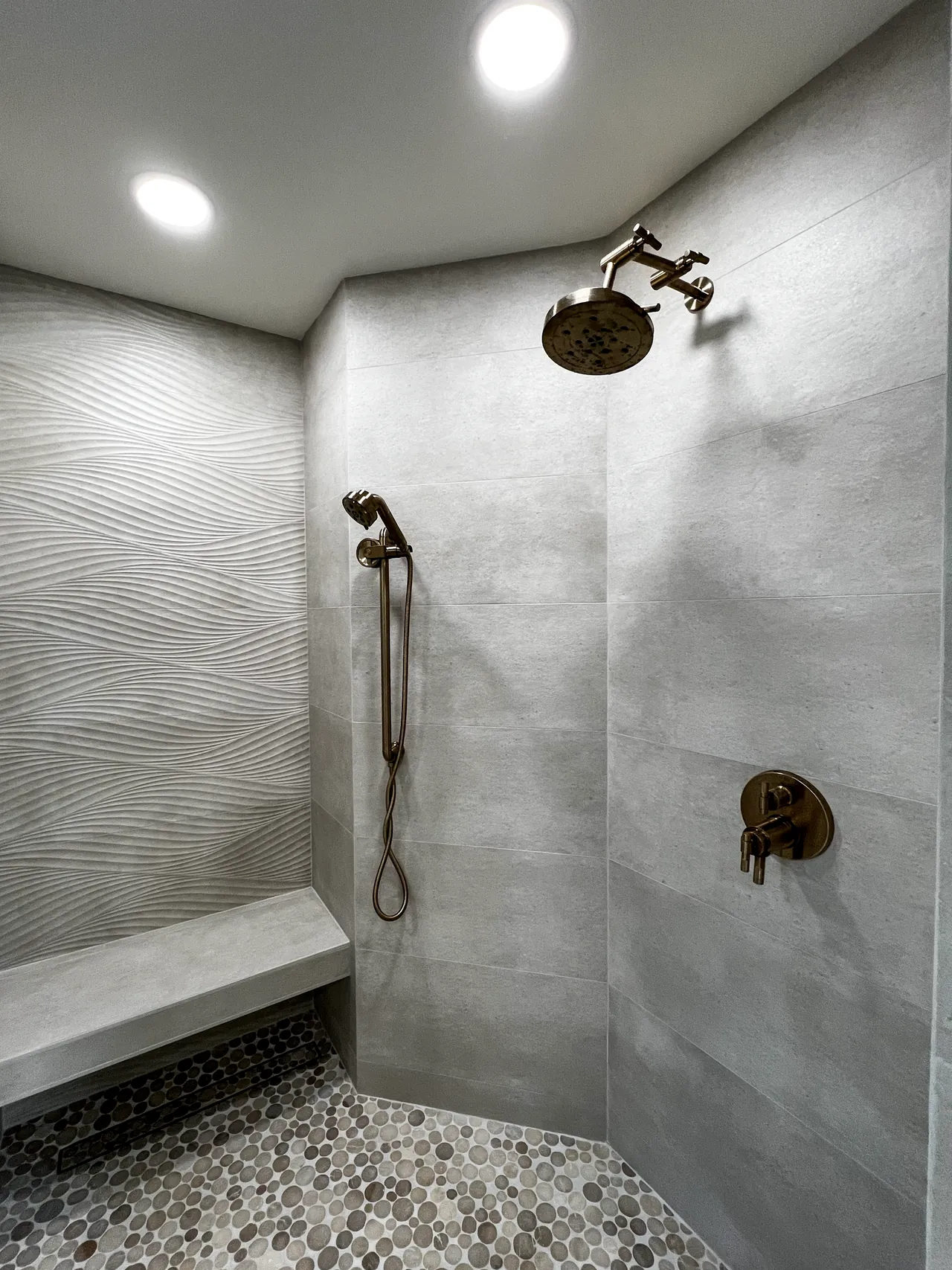 Walk-in shower with a floating bench, wave-pattern tile wall and pebble floor
