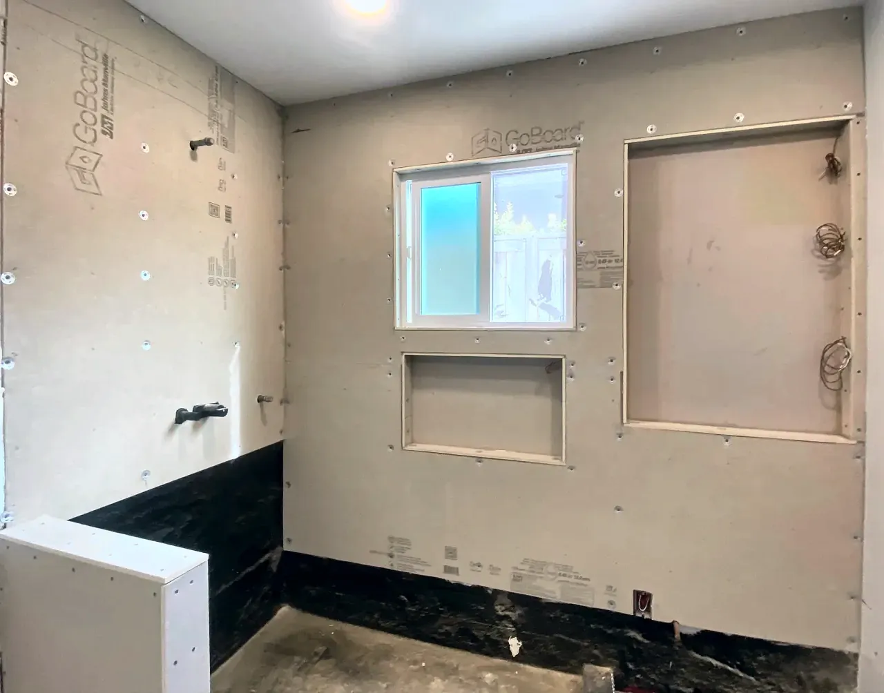 Waterproof backer board with the niche openings framed, before tile