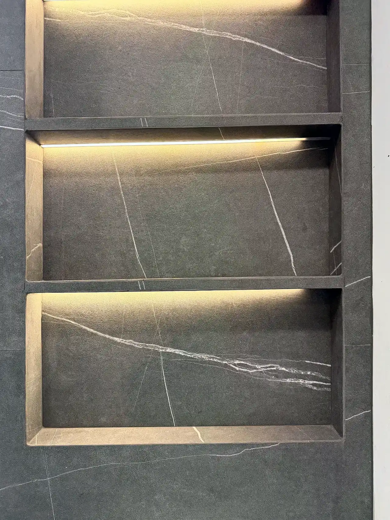 Three stacked wall niches with hidden LED strips and mitered tile edges