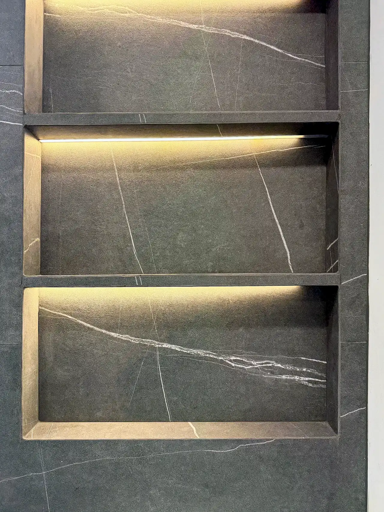 Three stacked wall niches with hidden LED strips and mitered tile edges