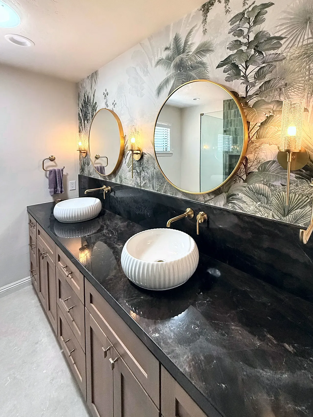 Guest bathroom in Fallbrook with botanical wallpaper, round brass mirrors and vessel sinks
