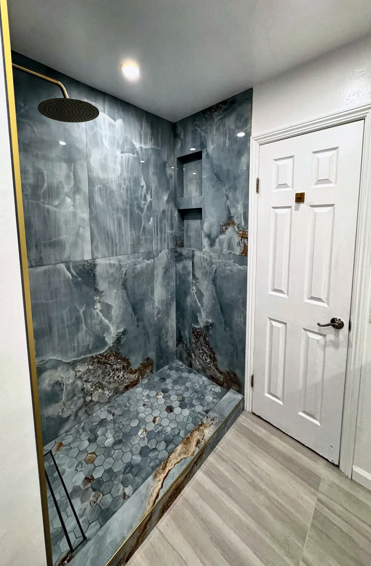Walk-in shower with blue onyx-look tile walls and a hexagon mosaic floor