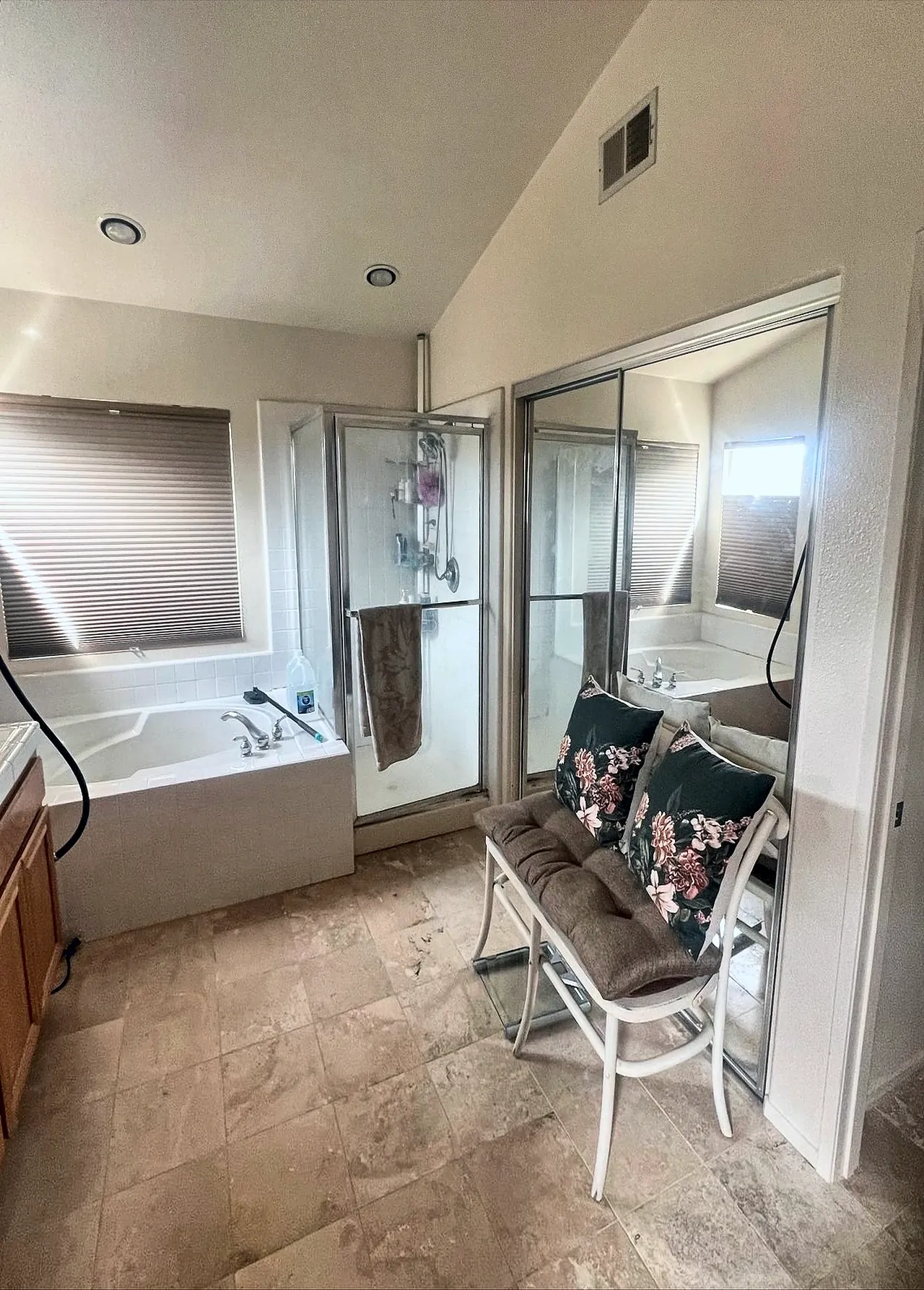 Primary bathroom before the remodel, with a drop-in tub in a tile deck under the window, a framed shower stall and a travertine-look floor
