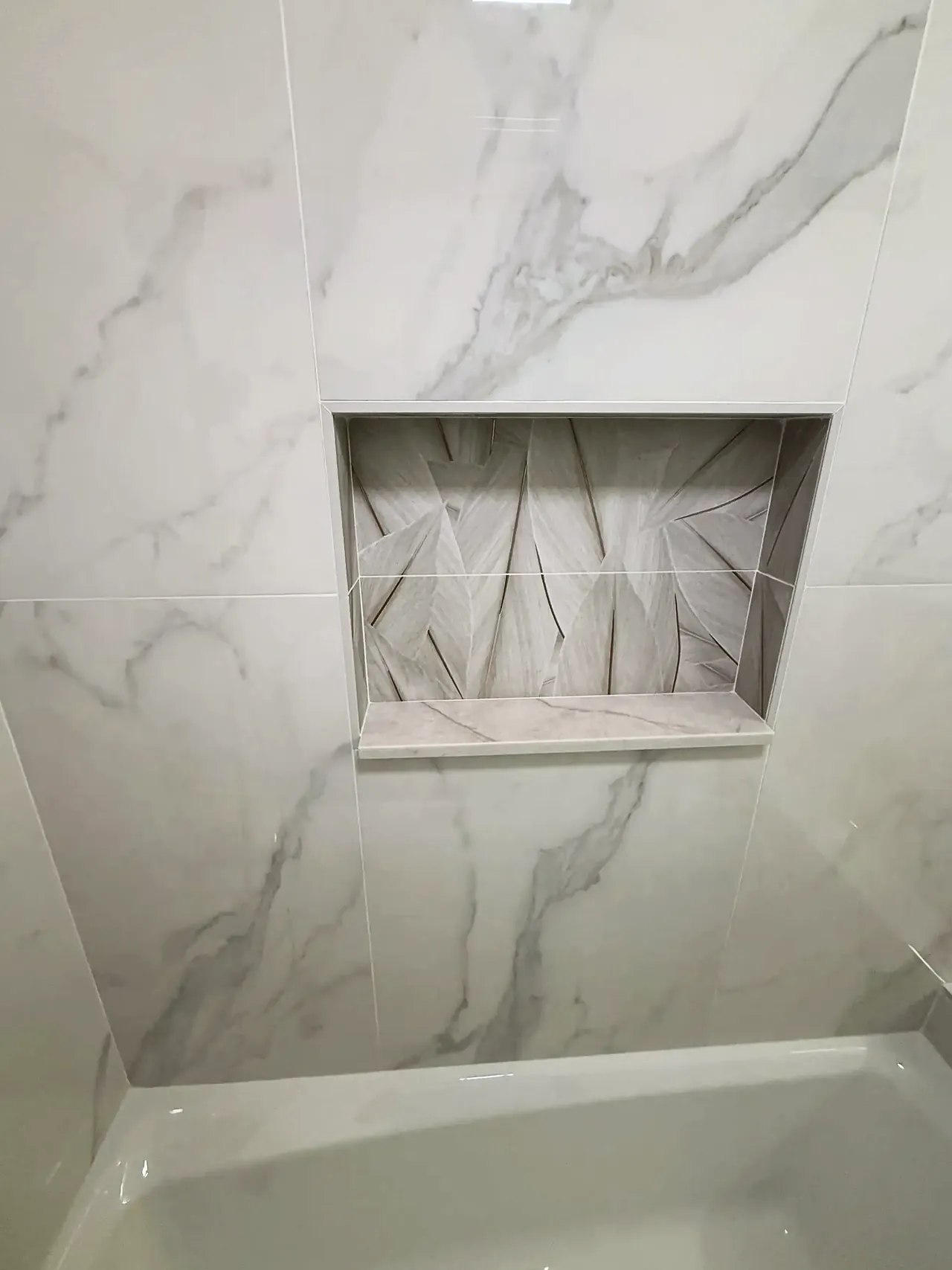 Tiled shower niche in the marble-look porcelain shower wall