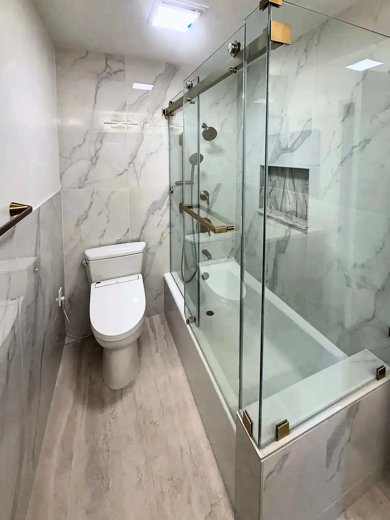 Marble-look tub and shower with frameless glass