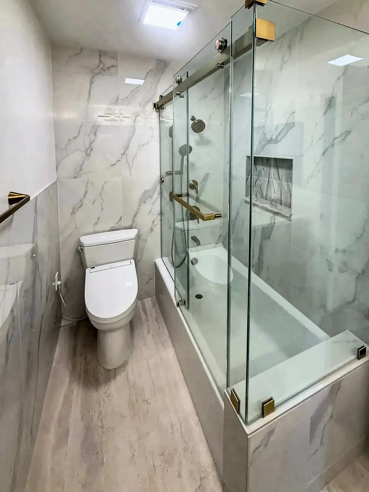 Marble-look tub and shower with frameless glass