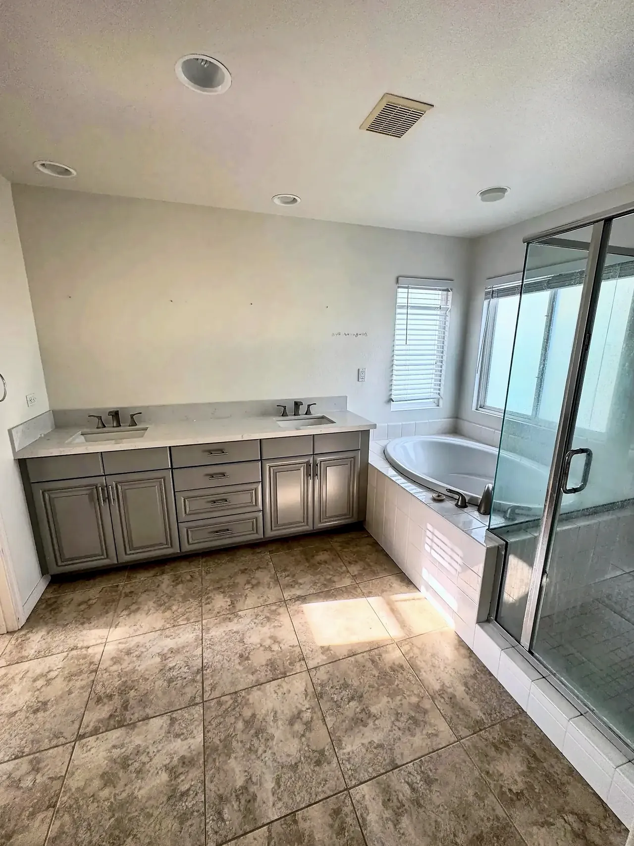 Primary bathroom before, with a raised-panel vanity and a tiled tub deck