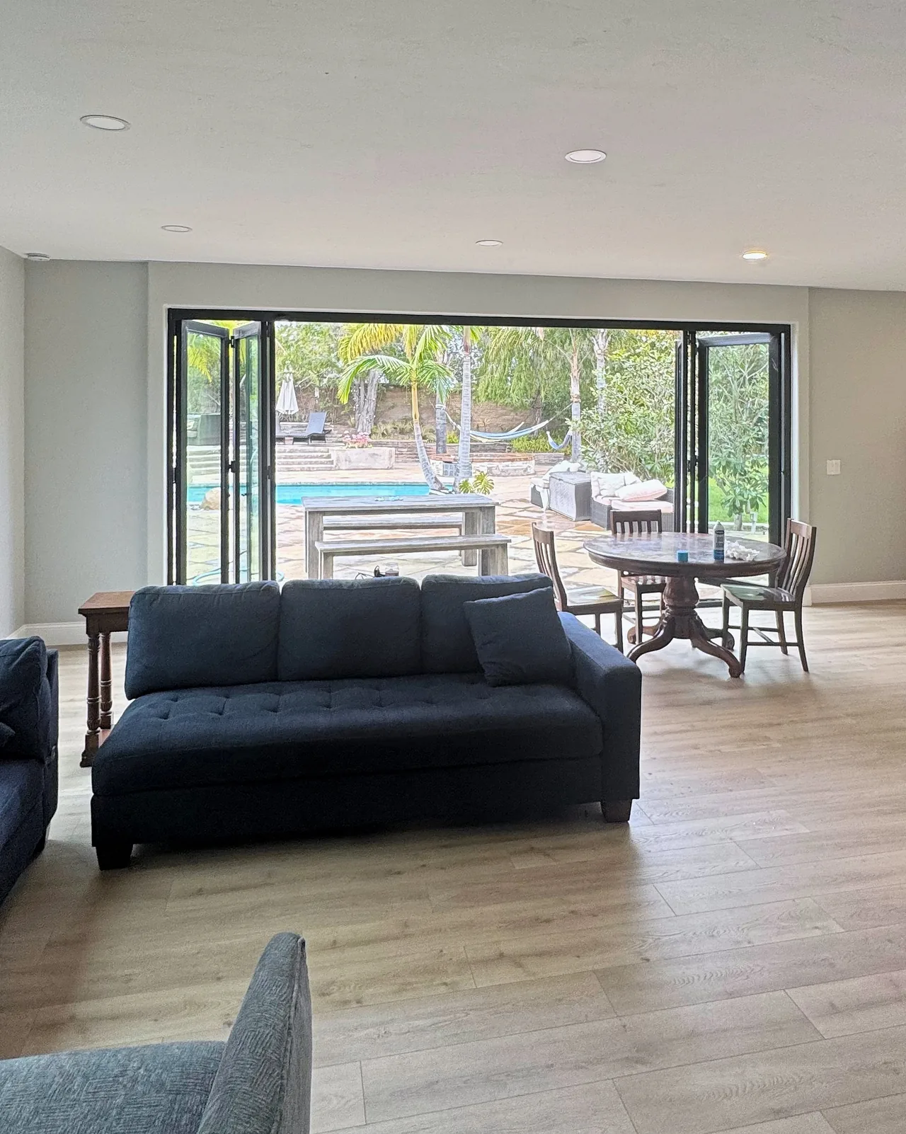 Family room with the six-panel black bifold door folded open to the patio and pool