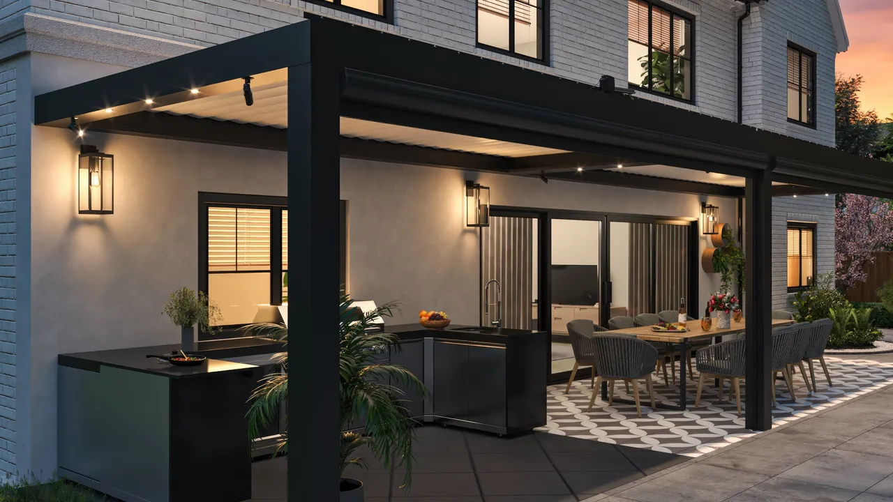 Black Equinox louvered roof lit at dusk over an outdoor kitchen and dining area