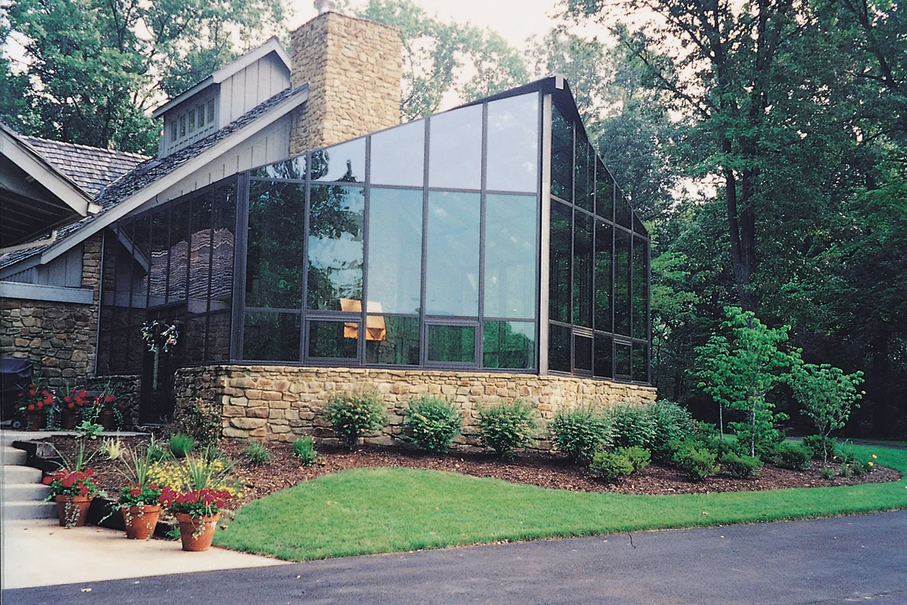 Four Seasons Cathedral sunroom with black frames on a stone base