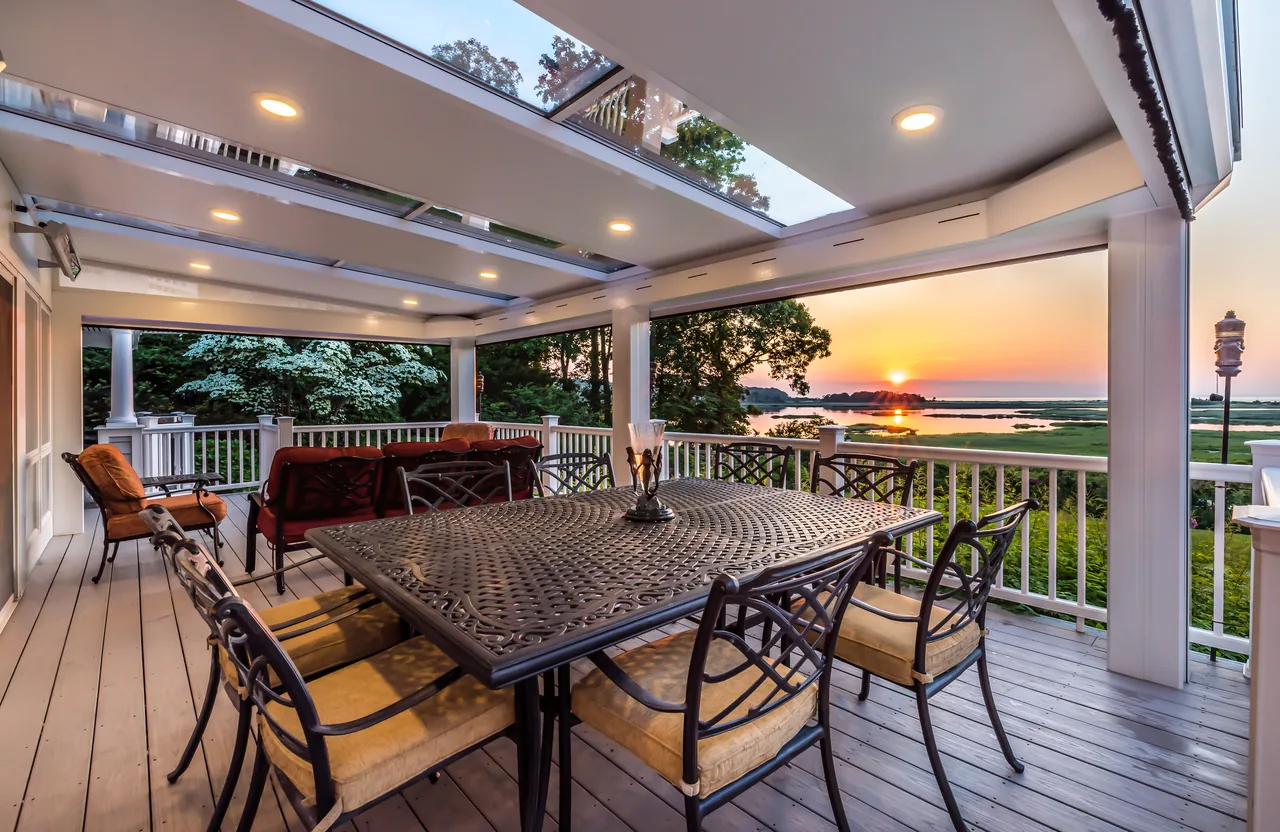 Four Seasons LifeRoom outdoor room on a deck at sunset, with a dining table and an ocean view