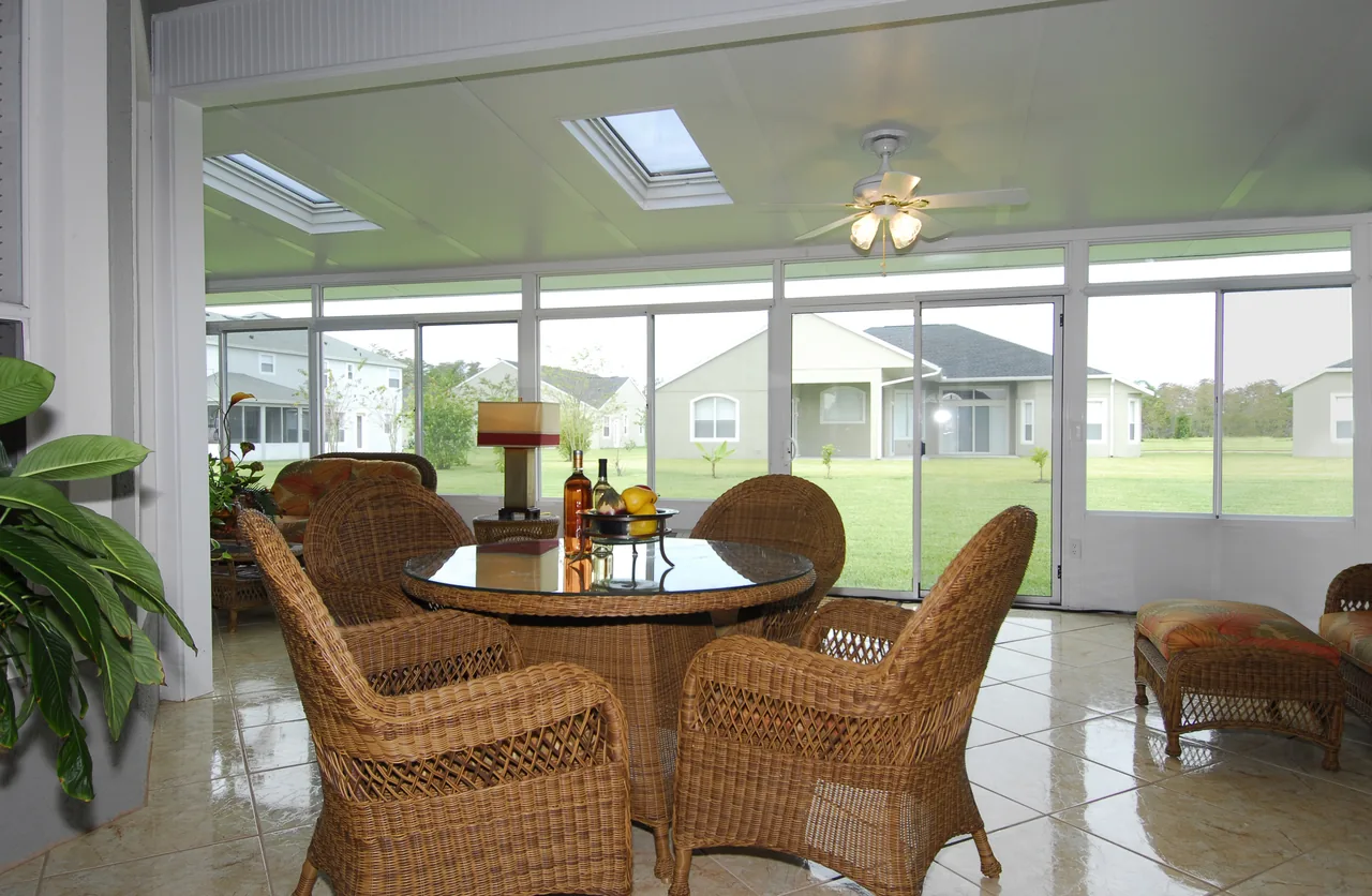 Four Seasons solid roof sunroom with a round dining table and a ceiling fan