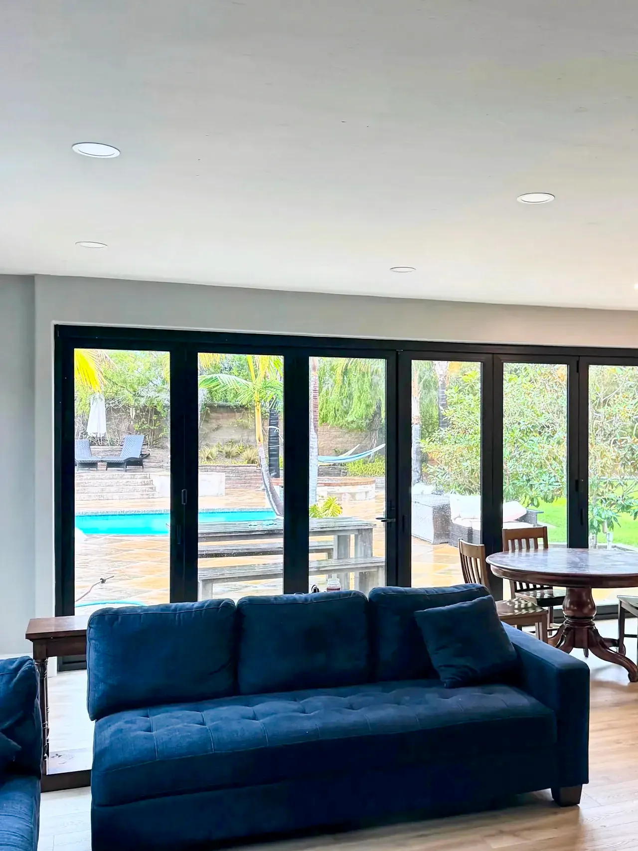 Carlsbad family room after, with a black bifold door opening to the patio and pool