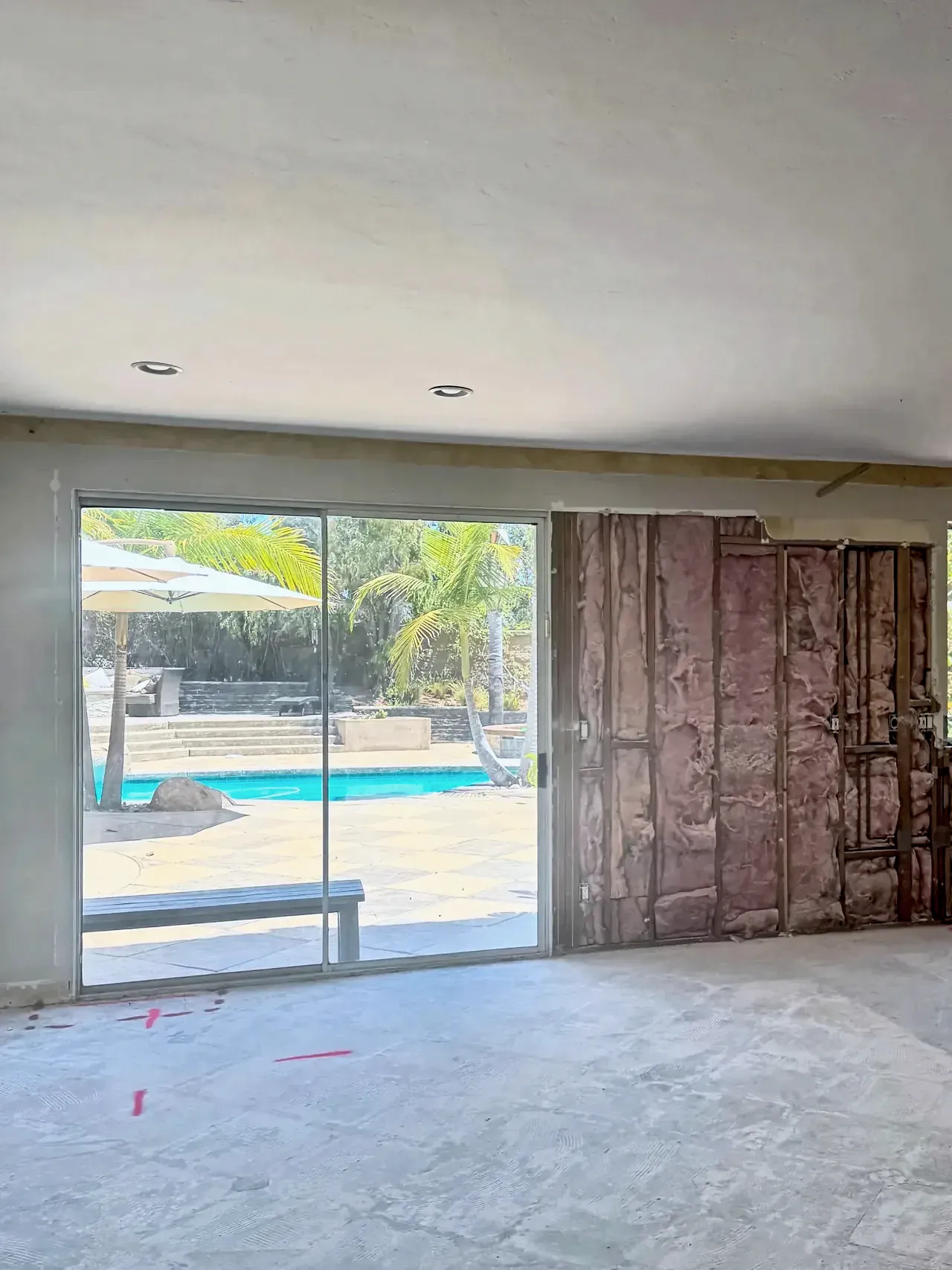 Carlsbad family room before, with an old sliding door and the wall beside it opened to the studs