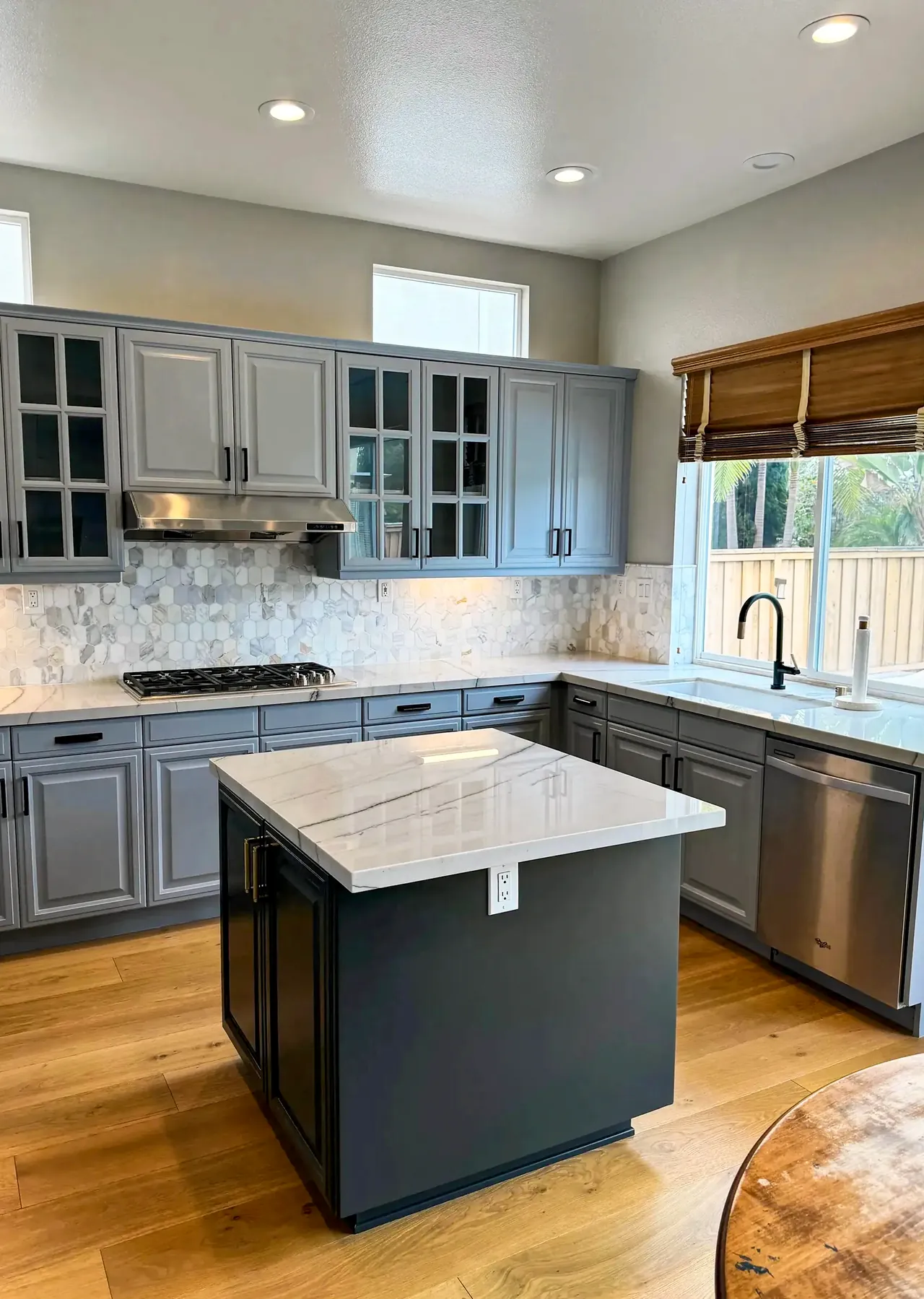The same Carmel Valley kitchen after, with gray painted cabinets, a charcoal island and wood floors