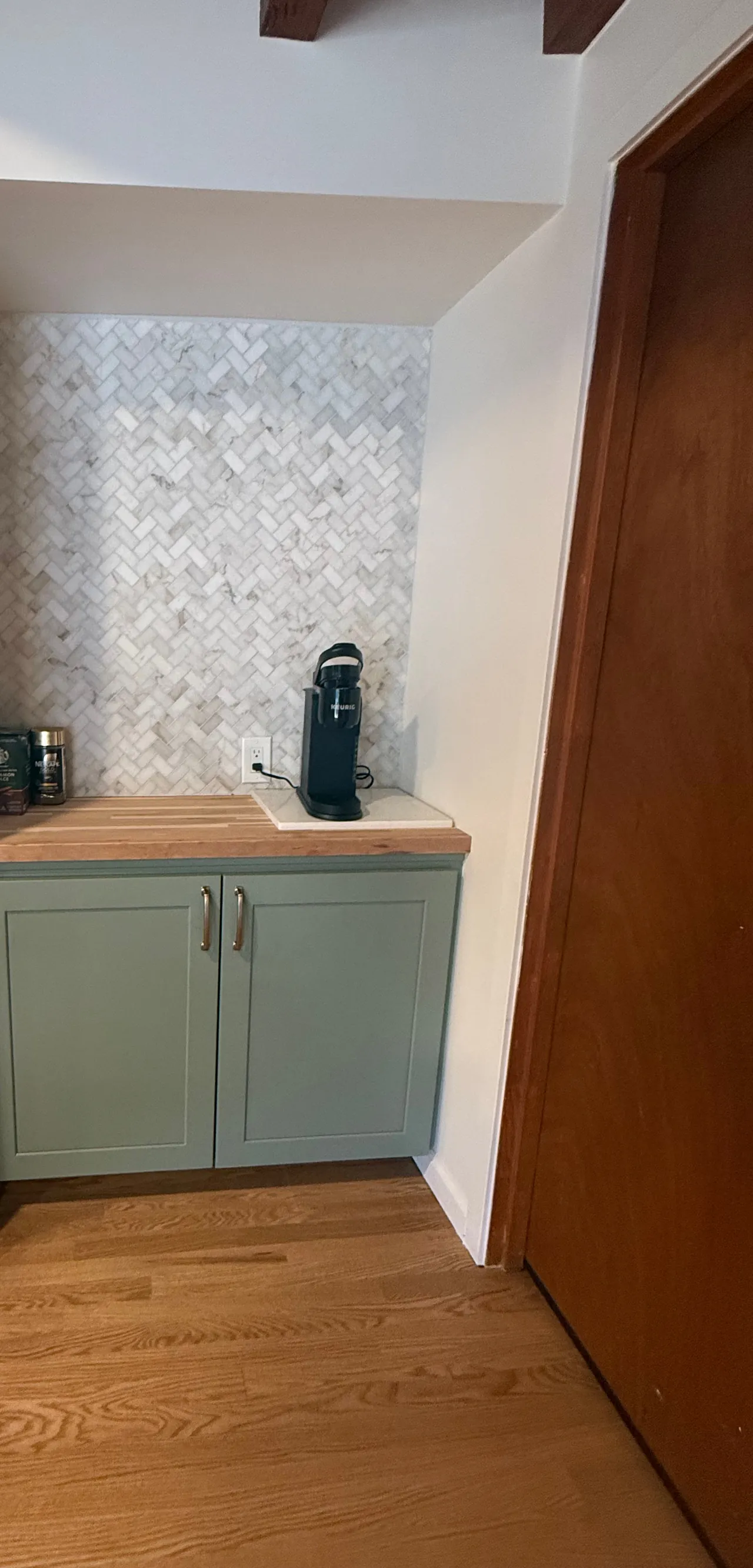 Coffee nook with sage green cabinets, a wood countertop and a marble herringbone backsplash