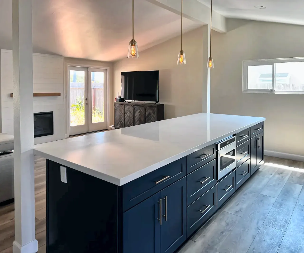 Long quartz island with navy cabinets and pendant lights