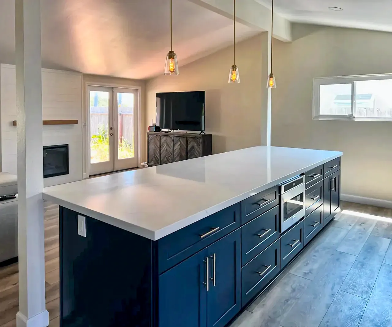 Long quartz island with navy cabinets and pendant lights