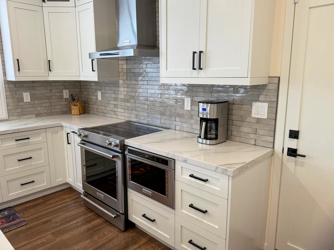 Slide-in range and a microwave drawer under the counter, with white shaker cabinets
