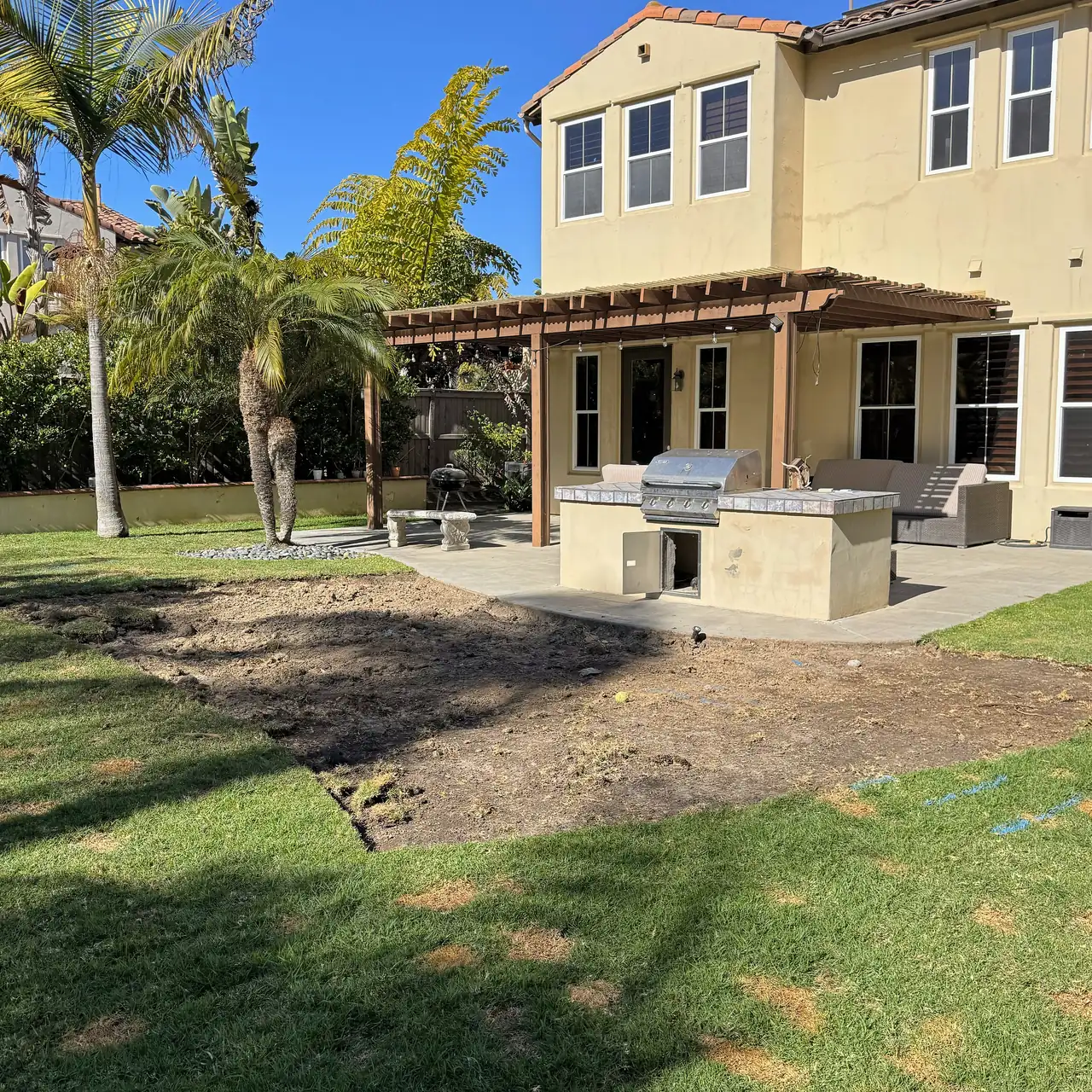 The backyard before the pool, a lawn behind the house with a patch of sod already lifted