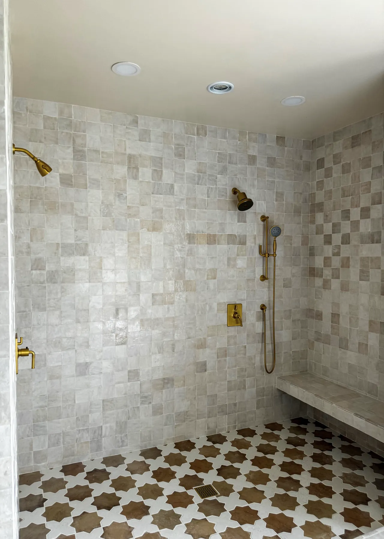 Walk-in shower with square wall tile, a tiled bench, brass fixtures and a star pattern tile floor