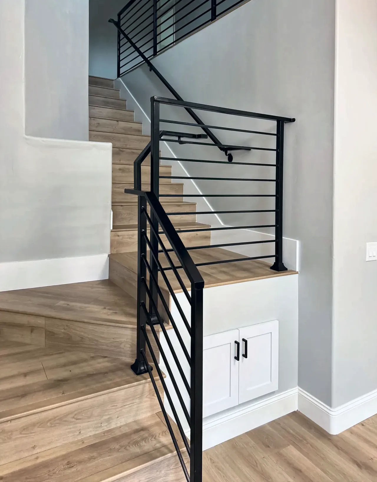 Rebuilt staircase with wood-look treads and a black horizontal-bar metal railing