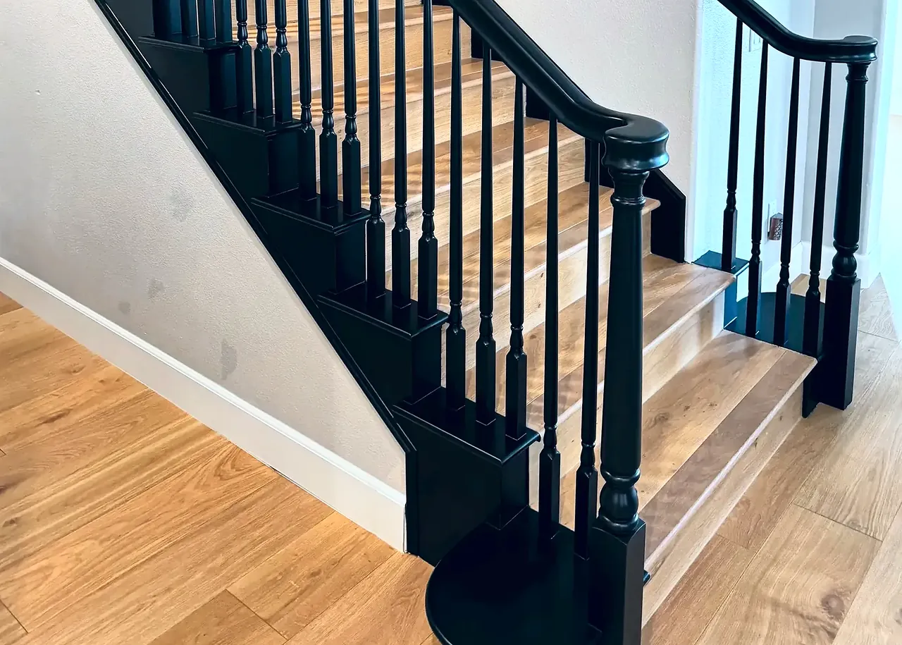 Banister painted black with new balusters over wood stair treads
