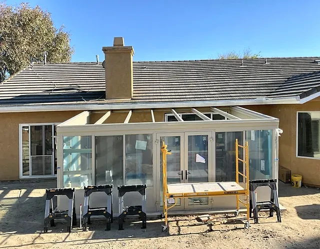 The sunroom frame and roof rafters going up on the patio slab