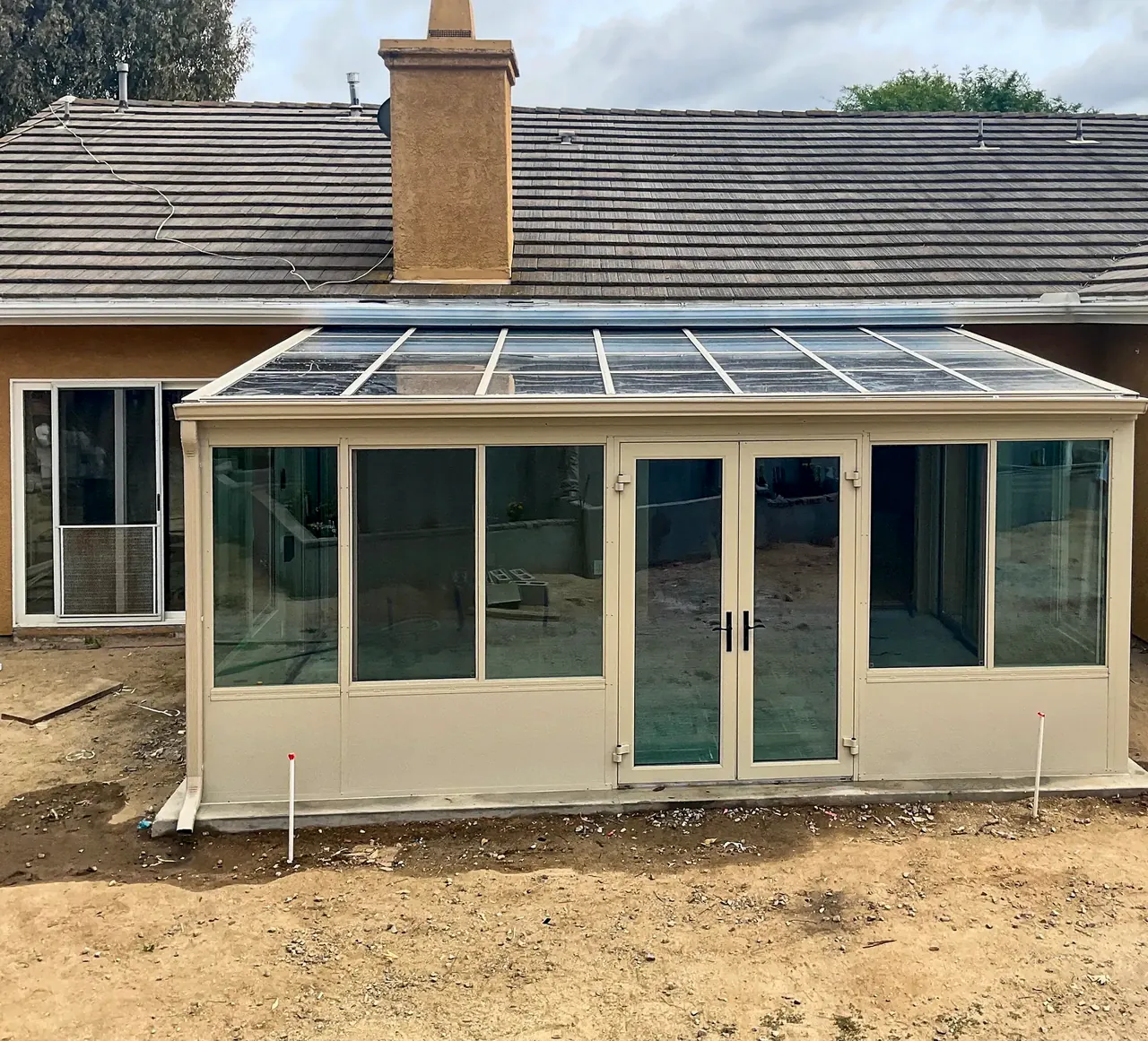 The finished sunroom in Fallbrook from the yard, with its glass roof, French doors and sliding windows