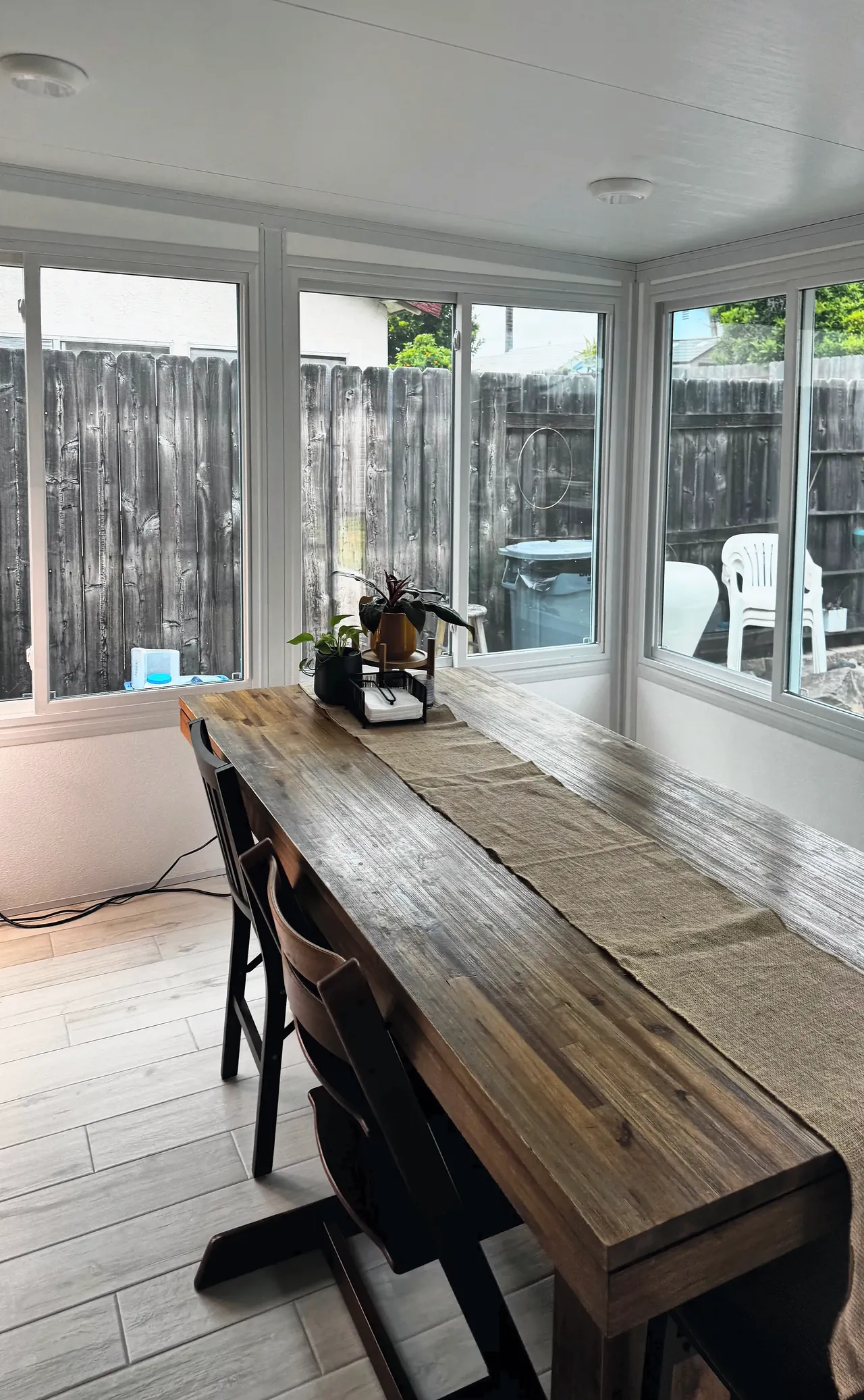 The finished sunroom in use as a dining room, with windows on two walls looking out to the yard