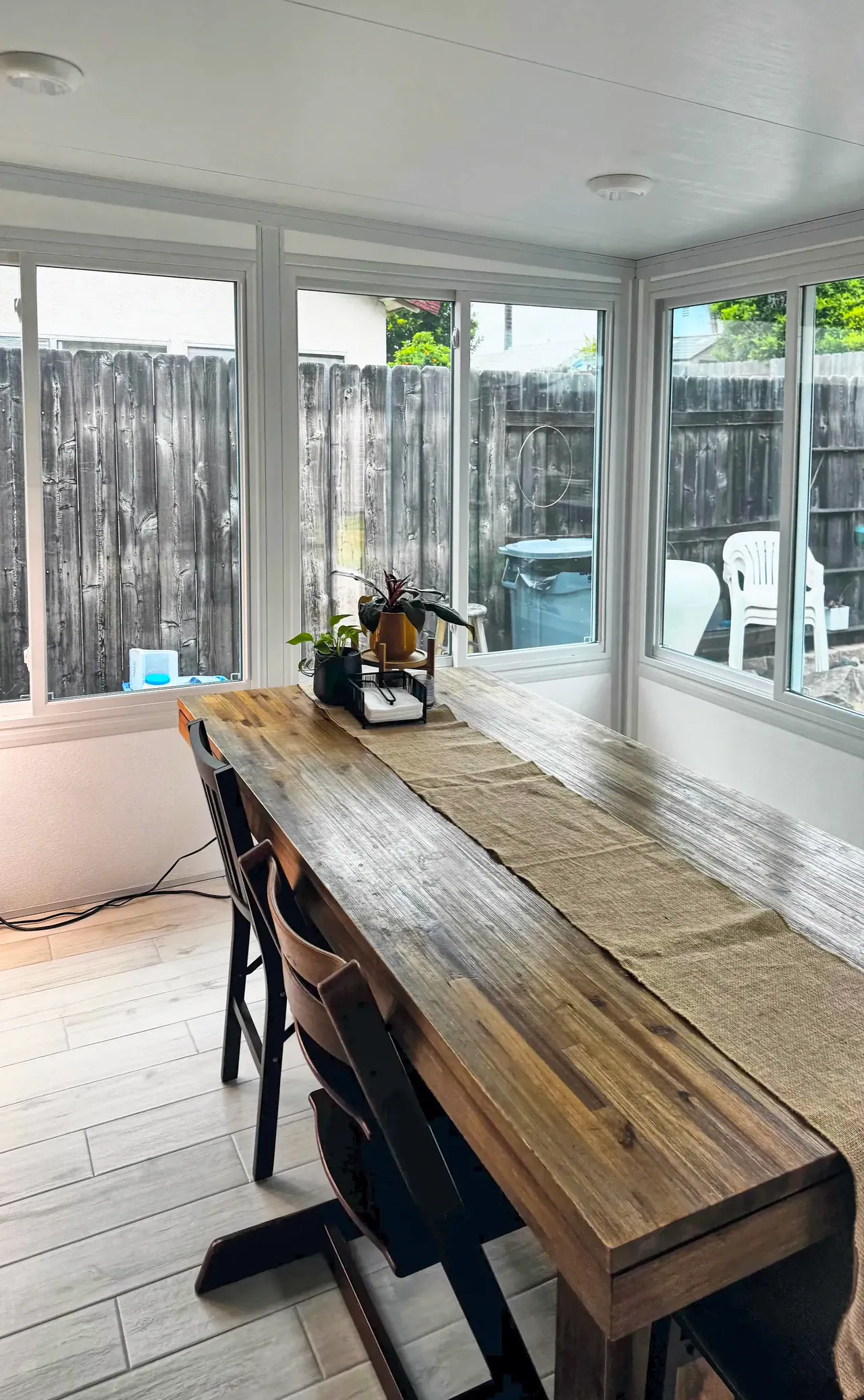 The Mira Mesa sunroom in use as a dining room, with windows on two walls looking out to the yard