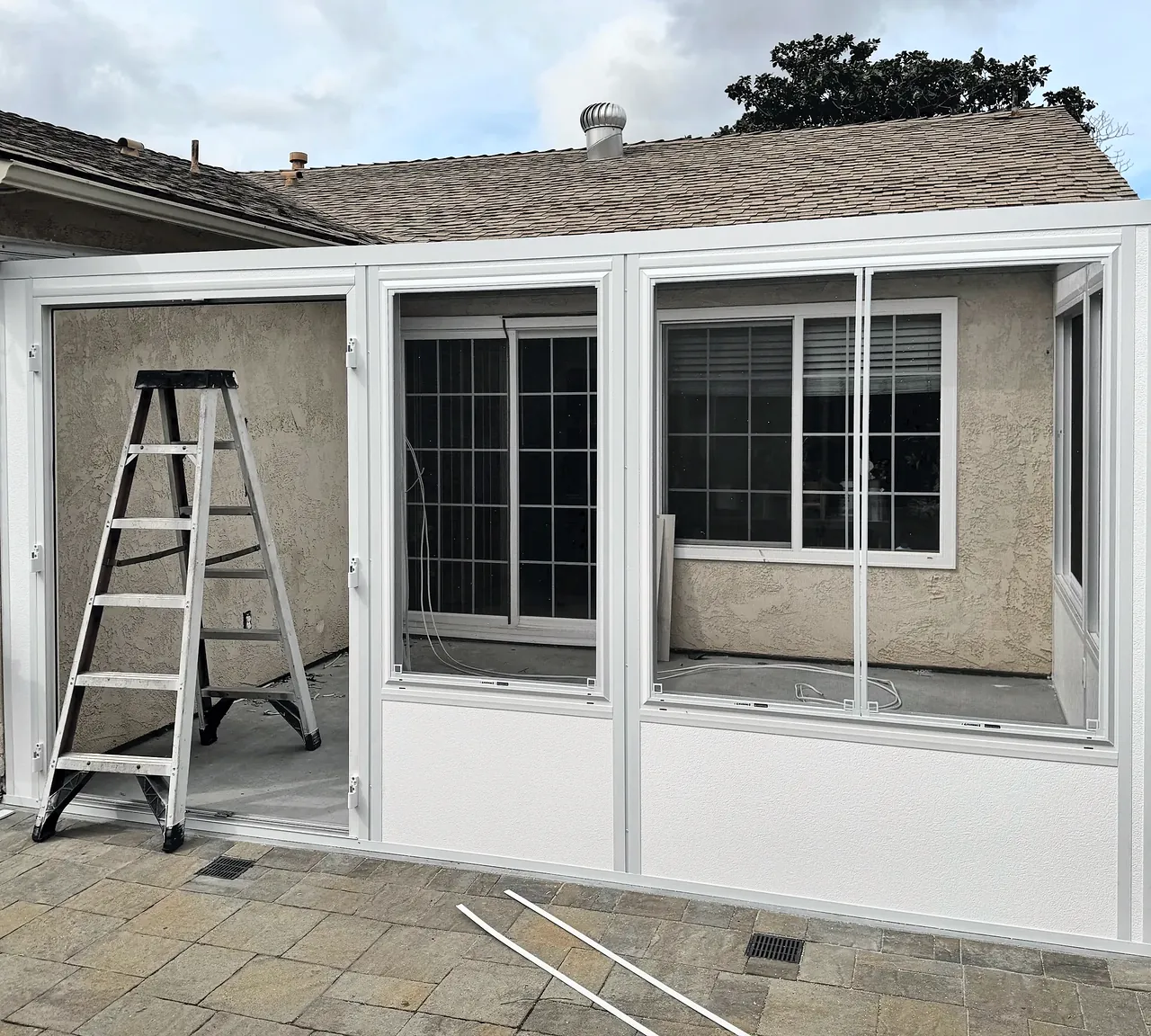 Sunroom wall frames and windows standing on the new slab against the house, before the roof went on