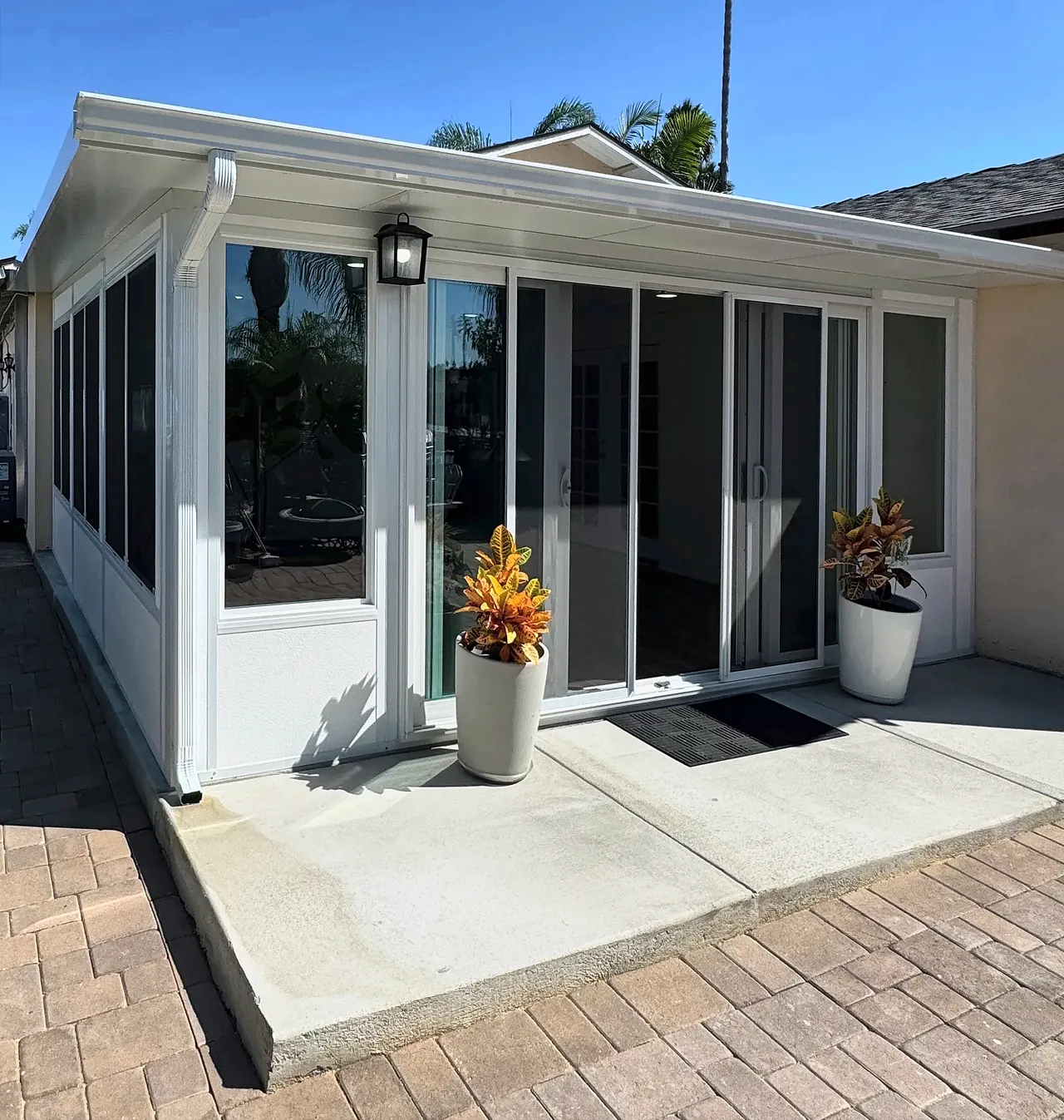 The finished sunroom from the corner of the patio, showing the row of windows along the side yard and the sliding glass door in front