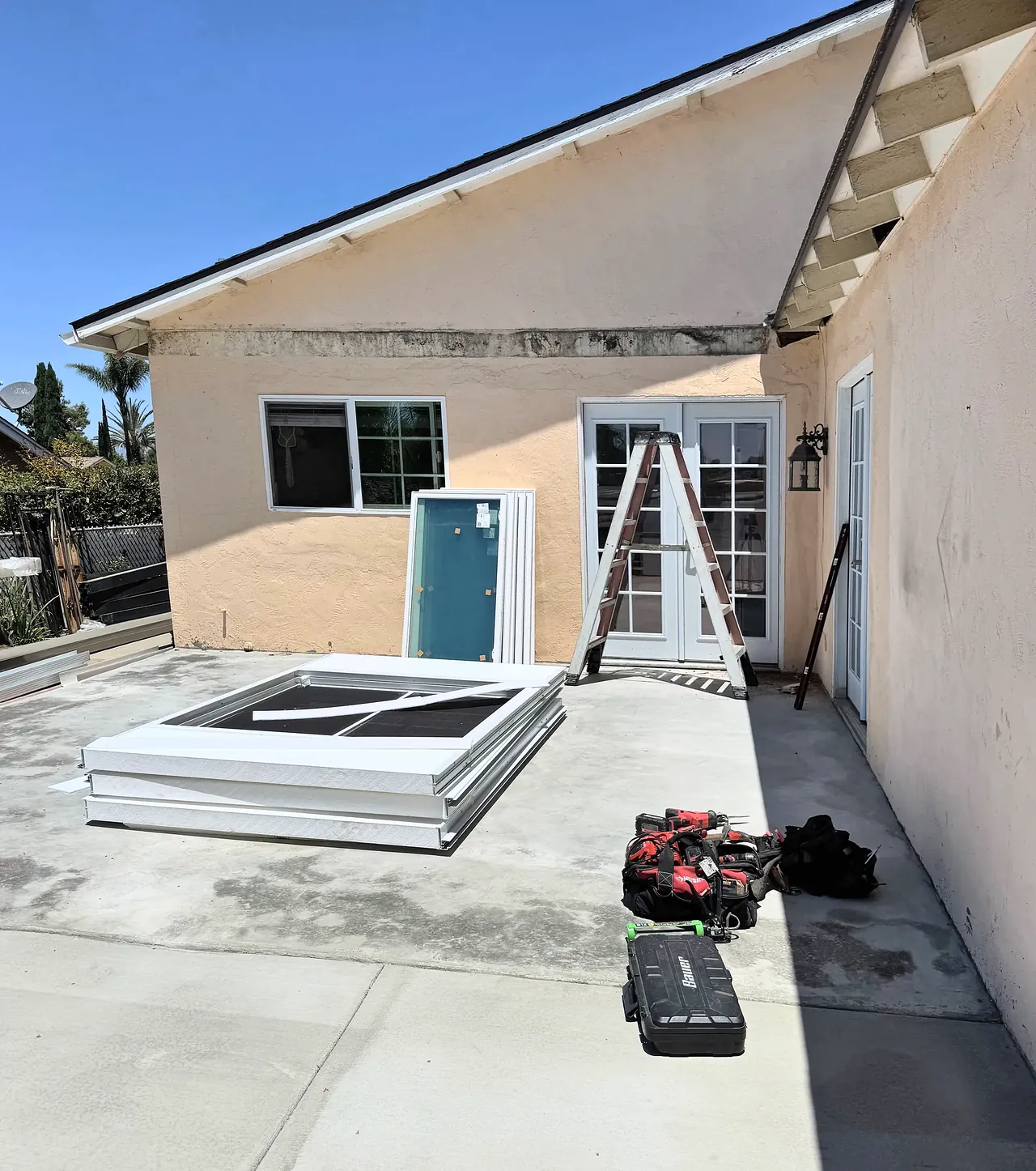 The new concrete slab poured, with the sunroom windows and frames stacked on it